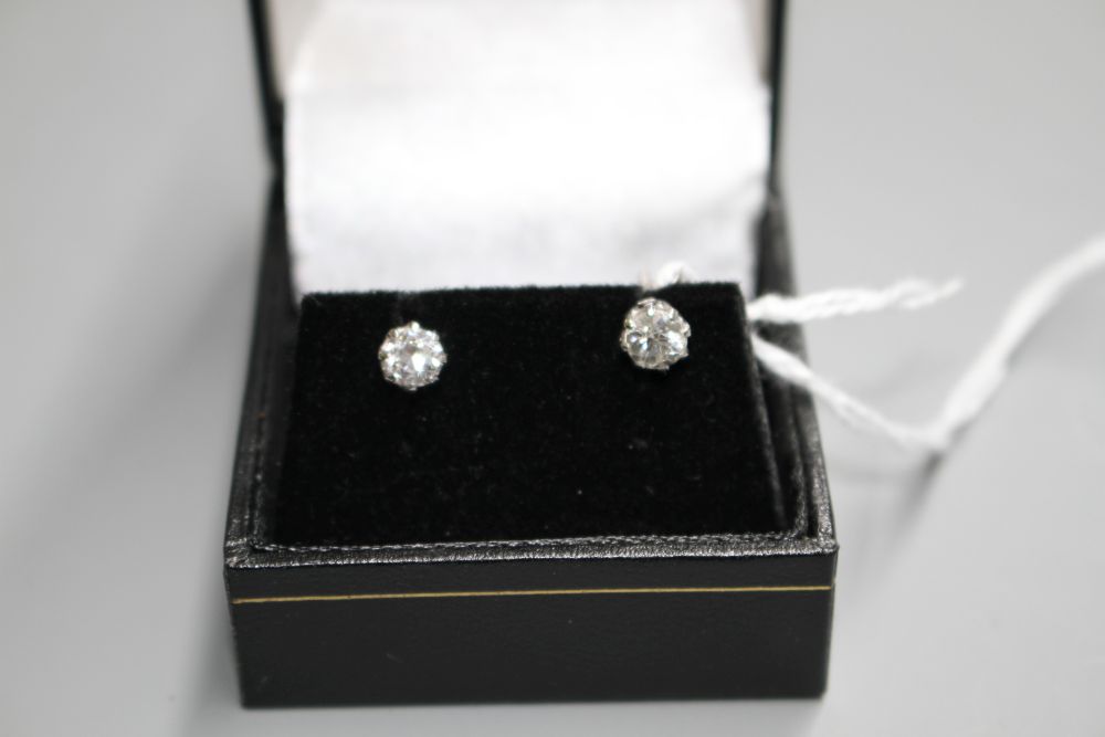 A pair of white metal and solitaire diamond ear studs,